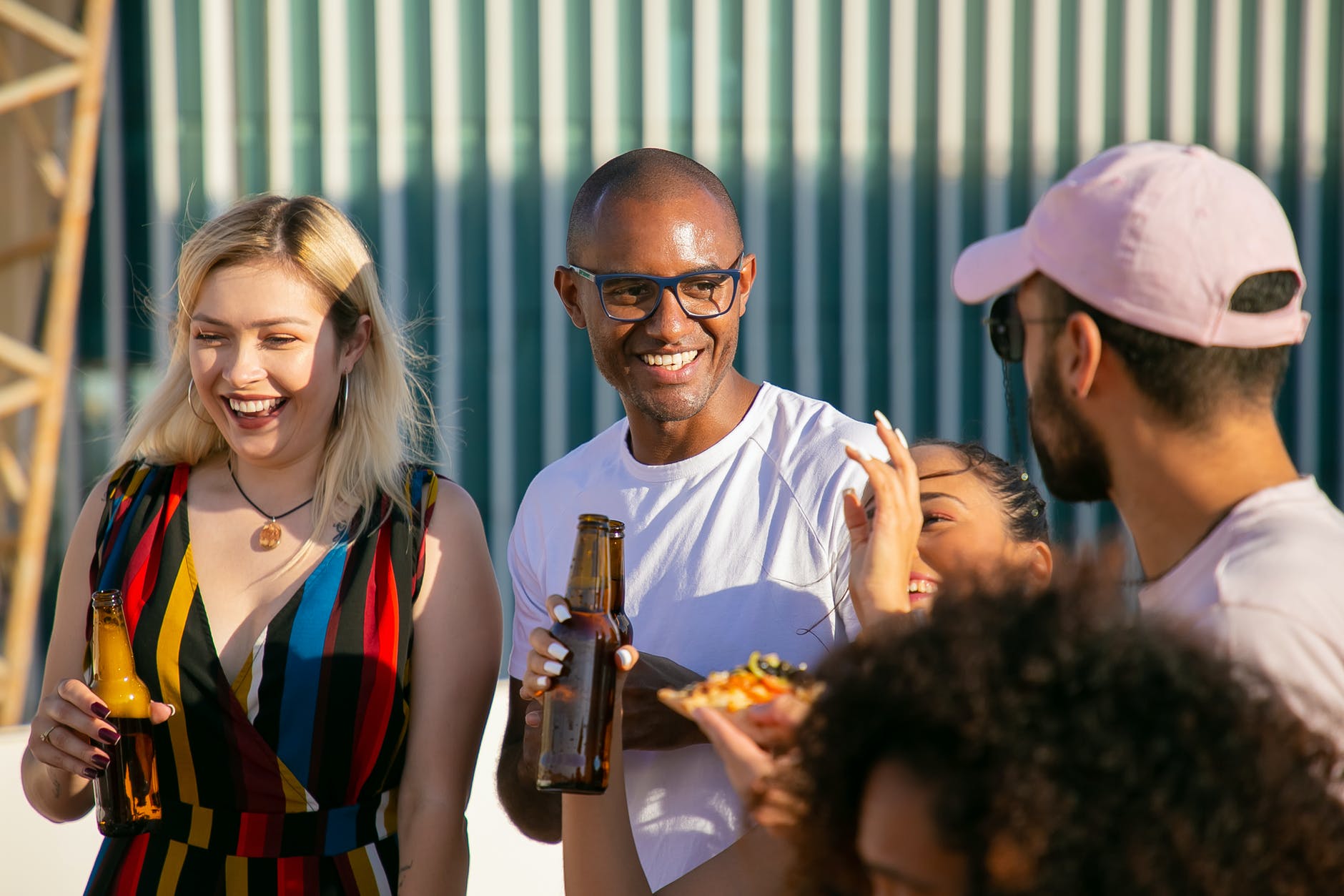 laughing diverse friends with beer bottles having party on terrace